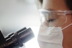 Person examining slide in microscope.
