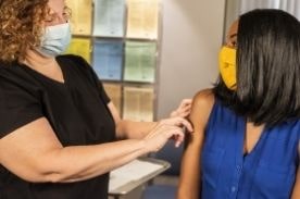 woman putting bandage on woman sitting.