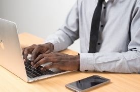 man typing on laptop.