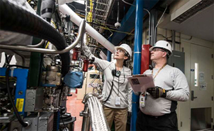 Workers inspecting manufacturing equipment.