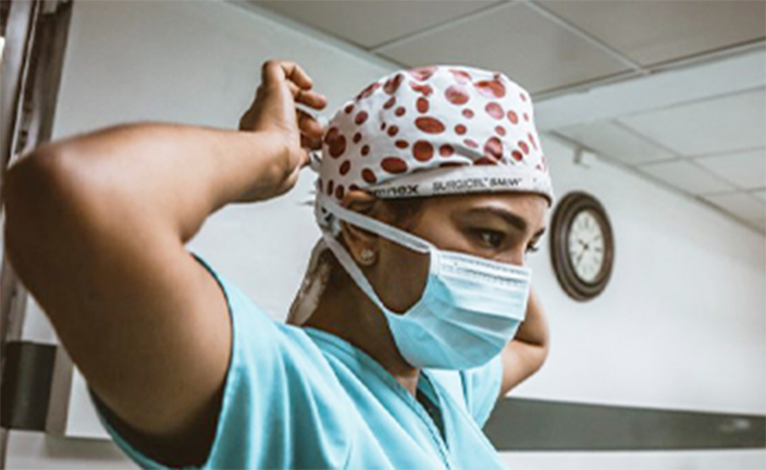 Person putting on surgical face mask.