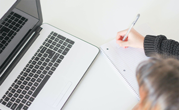 Woman taking notes with laptop.