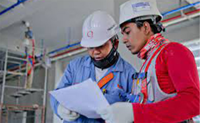 Two men in hardhats looking at paper.