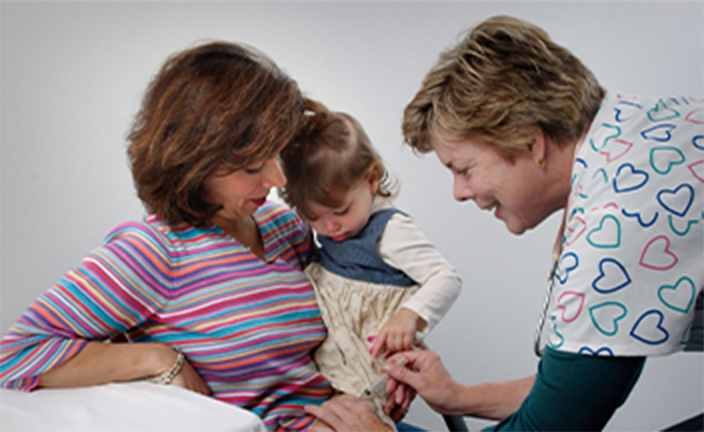 Medical assistant helping mother and child at exam.