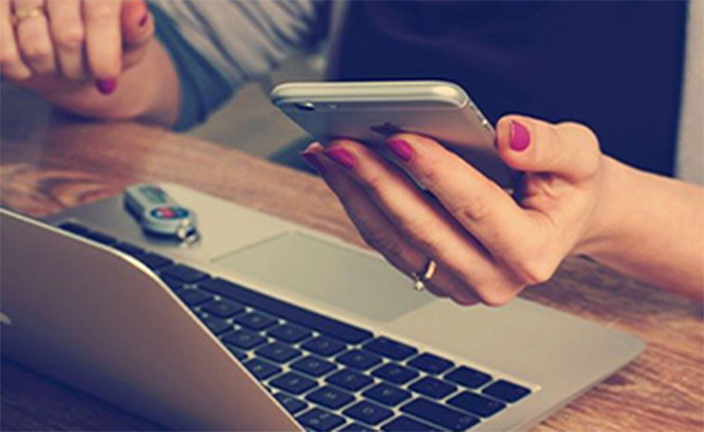 Woman using gray laptop and smartphone.