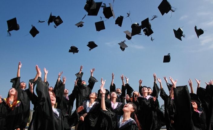 graduates throwing their caps in the air.