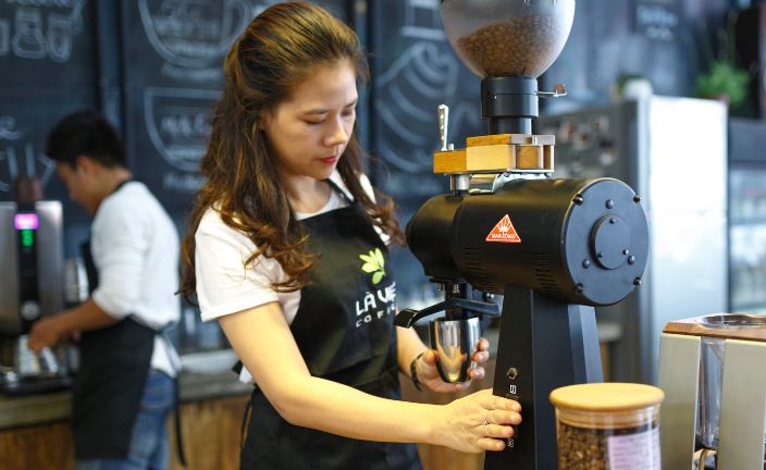 barista using espresso machine in coffee shop.