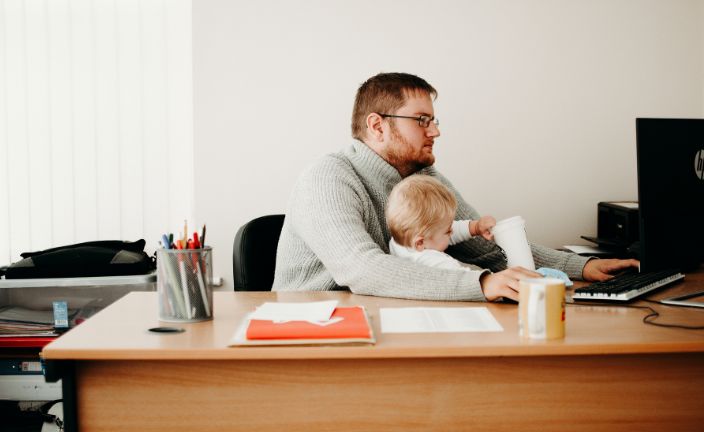 dad with child in his lap working at desk.