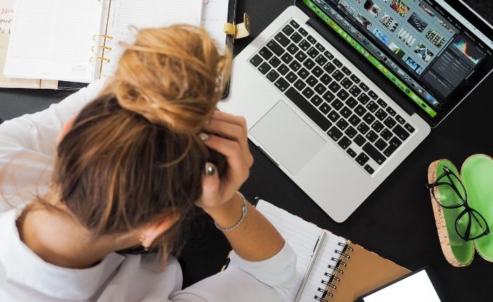 stressed woman with head in hands at her desk.
