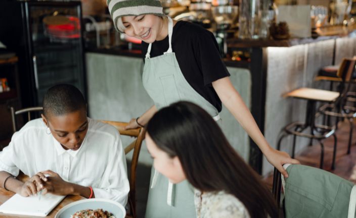 server helping two customers in cafe.