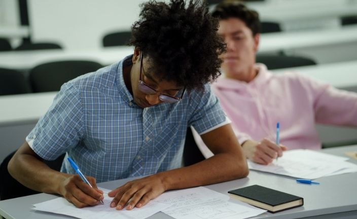 boy taking notes in classroom.