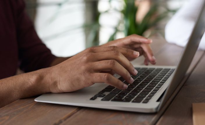 person typing on laptop outside.