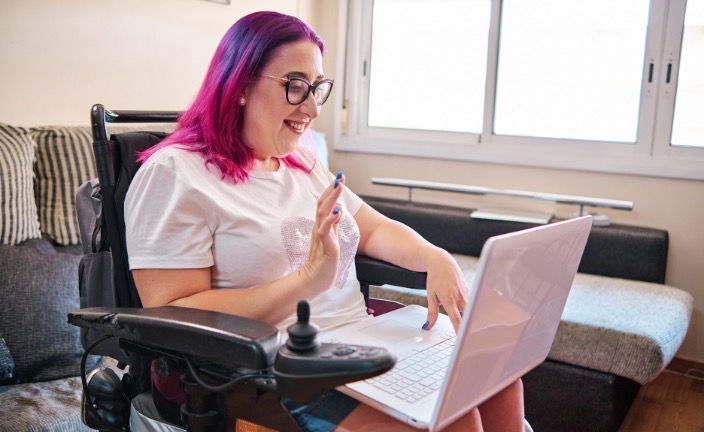Woman in wheelchair answering a video call on her laptop.