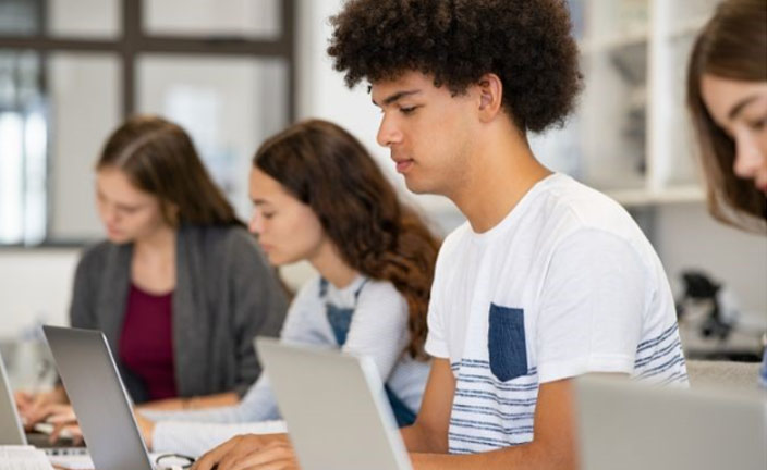 high school students working independently on laptops.