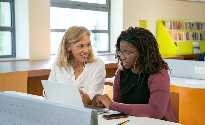 woman helping student working on laptop.