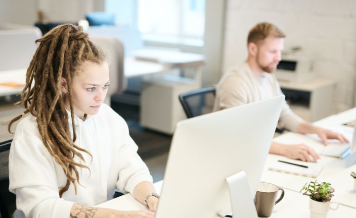 Workers at desk using desktop computers.