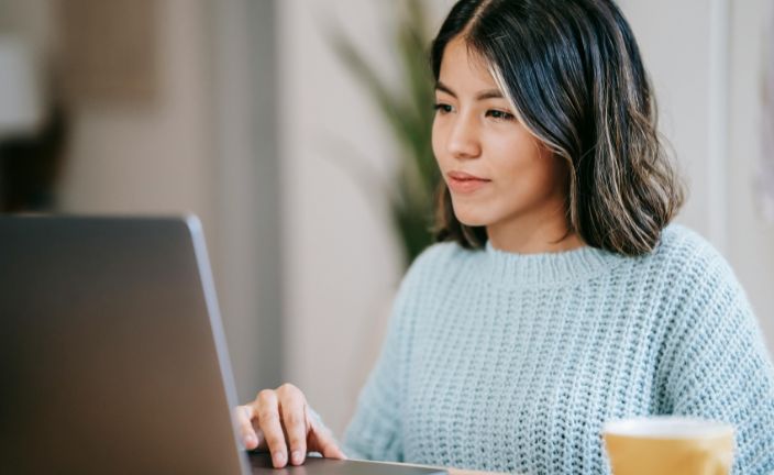 woman in blue sweater using laptop.