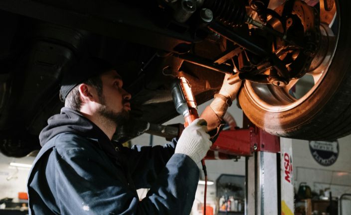 Mechanic working on car tire with flashlight.
