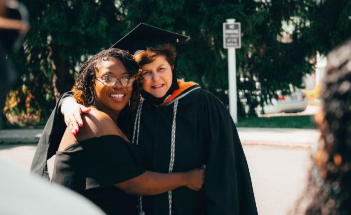 older woman in regalia getting photo taken with younger woman.