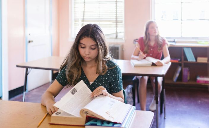 Two high school girls studying at desks in school.