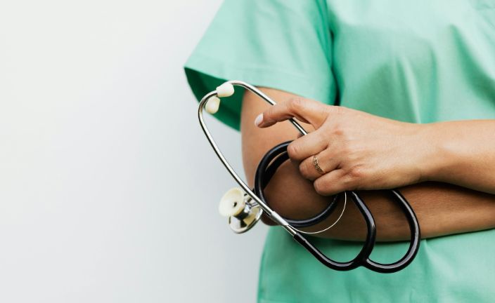 person in green scrubs with arms folded, holding stethoscope.