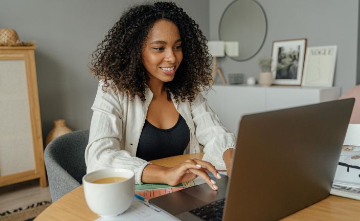 Women typing on laptop at dining room table.