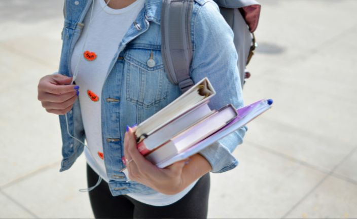 person wearing headphones and holding books.