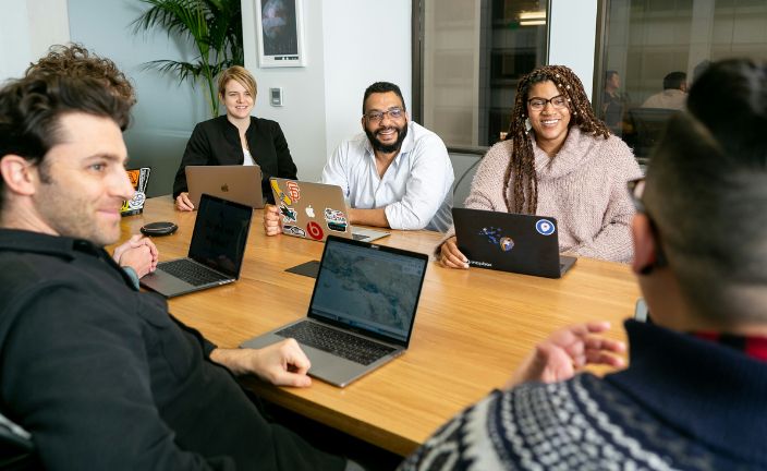 Workers sitting at a table on laptops.