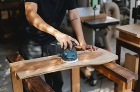 man sanding wood with power tool.