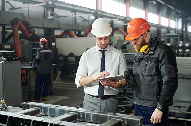 Two manufacturing workers checking the status of their project in a warehouse.