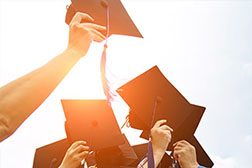 Graduation caps being held in the sunlight.