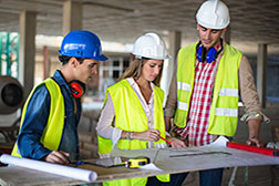 Construction trades workers evaluating a blueprint on a construction site.
