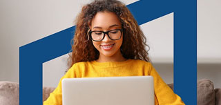 Girl in yellow sweater wearing glasses using laptop.