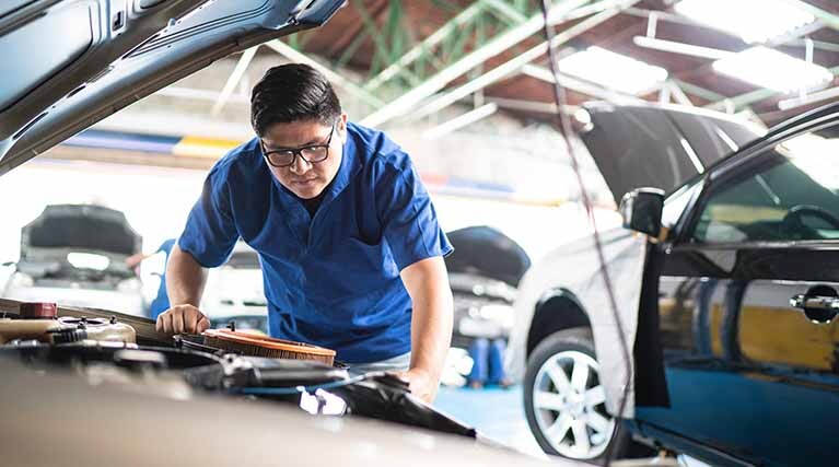 man looking under the hood of a car.