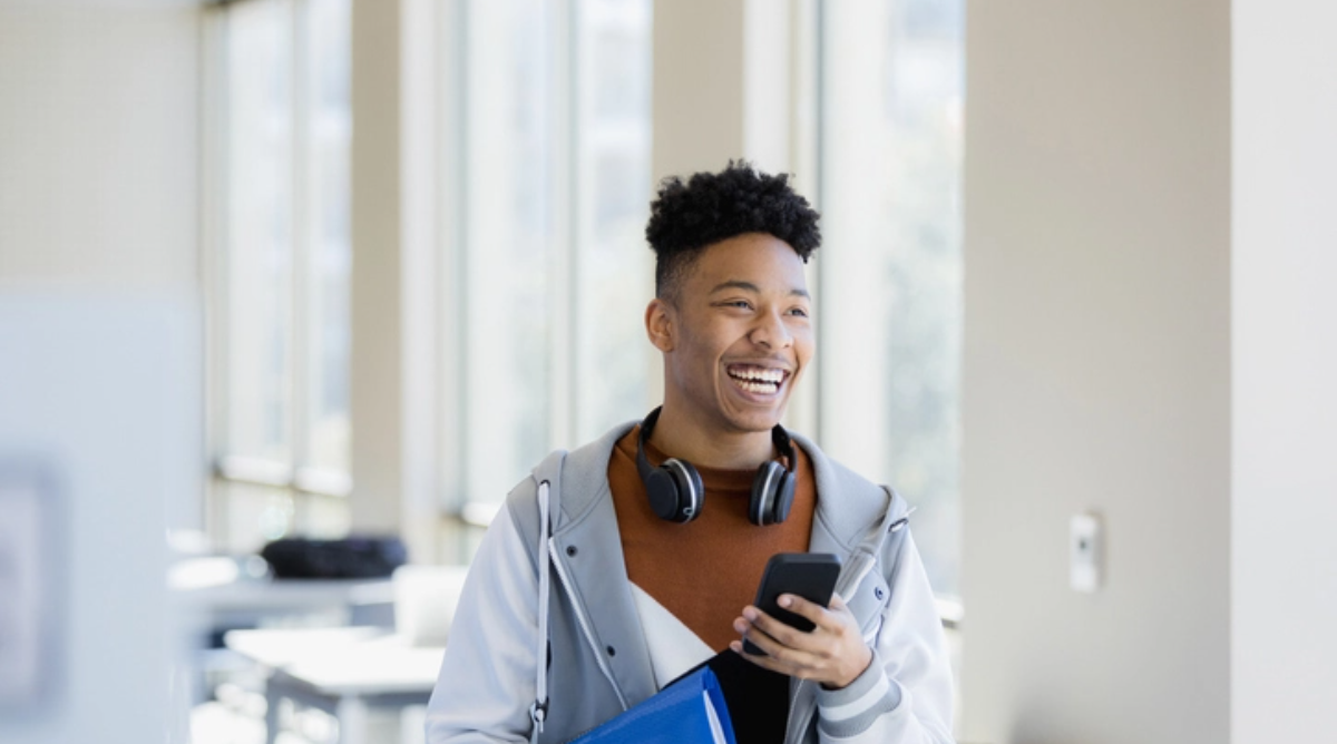 a student wearing headphones around his neck and smiling