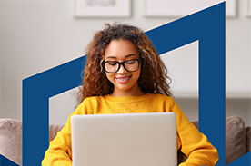 Girl in yellow sweater wearing glasses using laptop.