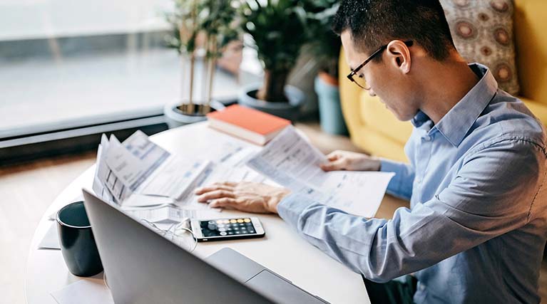 man sitting at a desk with papers and a calculator.