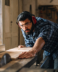 carpenter using table saw in workshop.