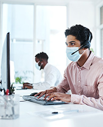 man sitting at a computer with a mask on.