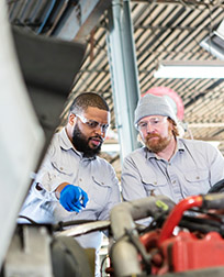 two mechanics inspect truck engine.