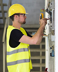 Apprentice electrician fixes wiring on a housing unit.