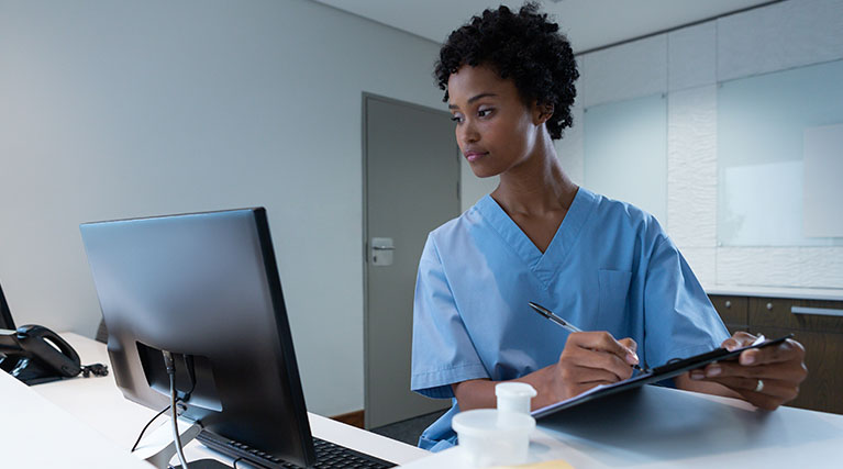 medical records technician reading computer screen and taking notes