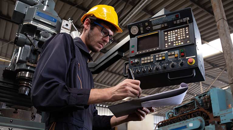 Maintenance Technician takes notes from a machine.