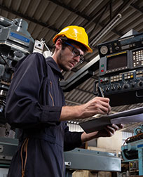 Maintenance Technician takes notes from a machine.