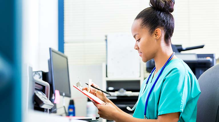 health professional looking at a chart in front of a computer.