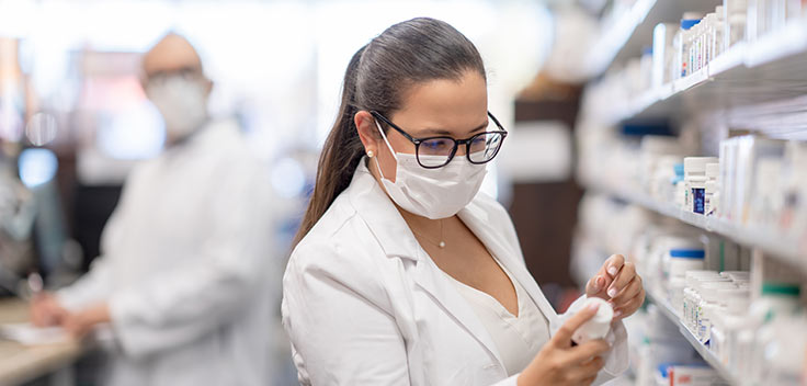 Pharmacist organizing medicine on a pharmacy shelf.
