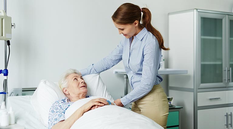 woman by a patient’s bedside in a hospital.