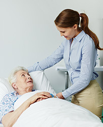 woman by a patient’s bedside in a hospital.