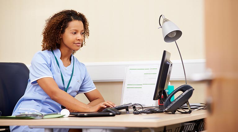 woman sitting behind a desk on a computer.