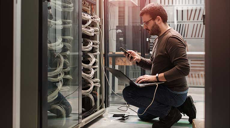 IT technician using laptop in server room